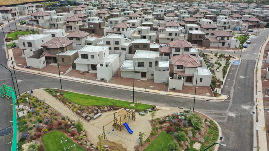 Plaza con juegos infantiles y paisajismo frente a casas nuevas