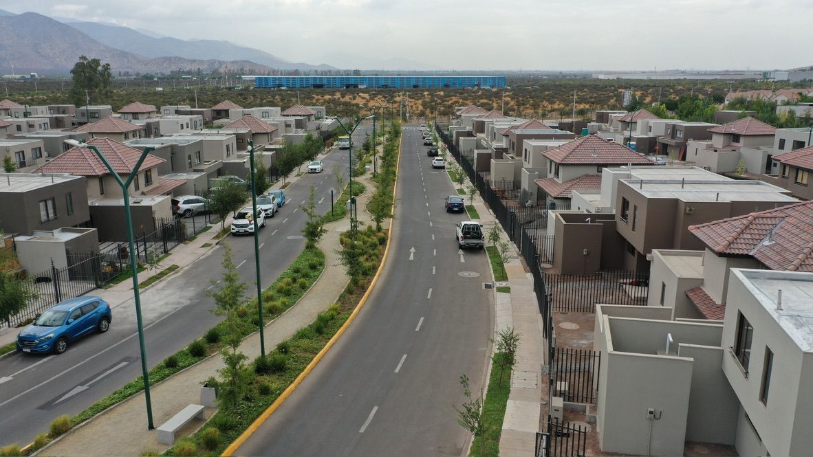 Avenida arborizada con casas nuevas en un loteo del poniente de Santiago